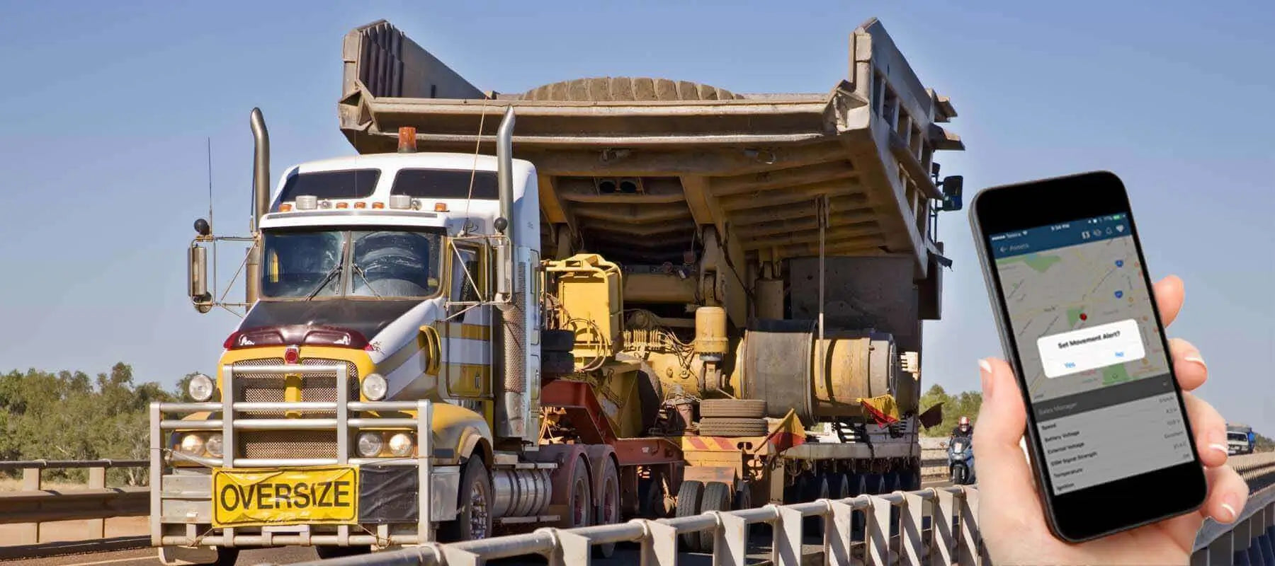 Road train transporting oversized mining truck to new site, ideal use case for battery-powered GPS trackers with movement-based updates in remote Australia